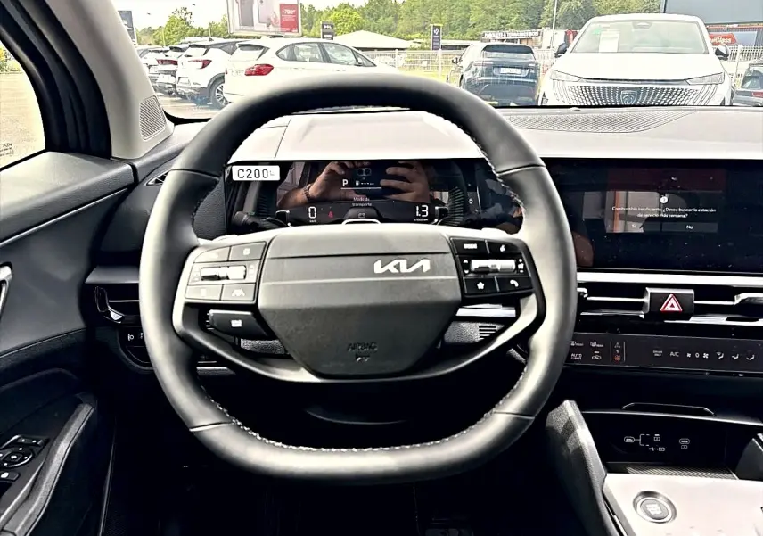 Vue intérieure centrée sur le volant noir multifonction du Kia Sportage 1.6 hybride 239, avec tableau de bord digital.