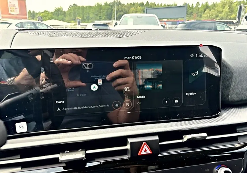 Écran tactile central du Kia Sportage 1.6 hybride 239, affichant navigation et mode hybride, intérieur noir.