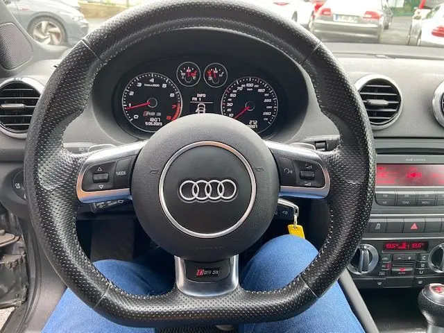 Vue centrée sur le volant cuir perforé de l'Audi RS3 Sportback 2012 avec tableau de bord et console noire.