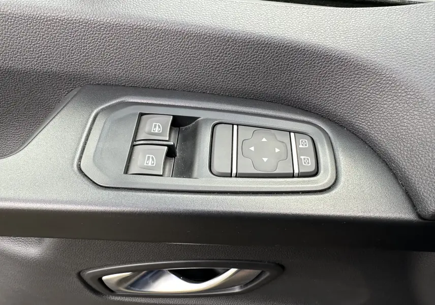 Détail des commandes de lève-vitres et réglage des rétroviseurs sur la portière intérieure noire du Renault Trafic Combi gris Comète 2023.