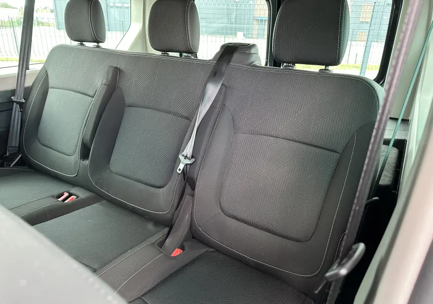 Vue rapprochée des sièges arrière noirs en tissu du Renault Trafic Combi 2023, version 9 places, avec ceinture de sécurité visible.