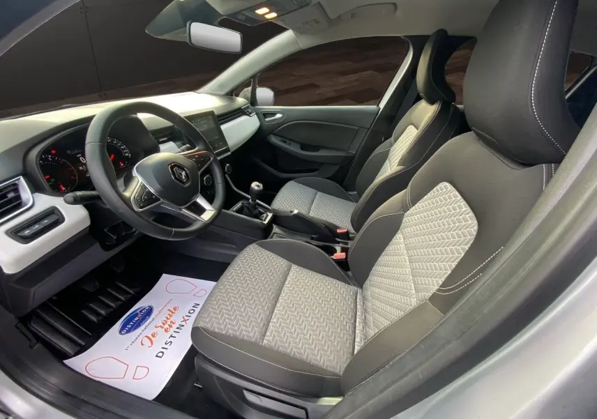 Intérieur avant de la Renault Clio V TCE 90 Evolution gris Highland avec sellerie beige et volant multifonction.