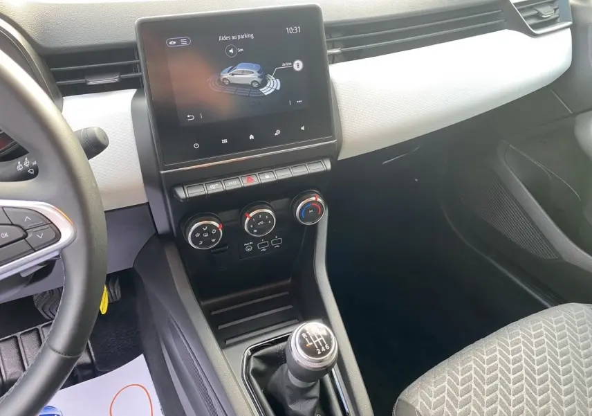 Intérieur de Renault Clio V TCE 90 Evolution, vue console centrale avec écran tactile, climatisation et levier de vitesse manuel.