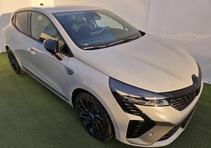 Renault Clio V hybride gris Rafale vue 3/4 avant gauche avec jantes noires et rétroviseurs noirs brillants.