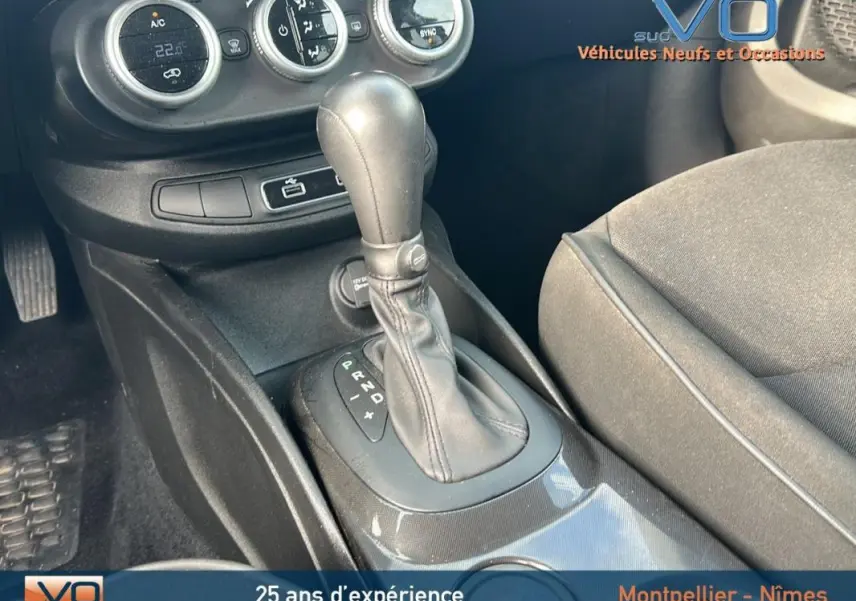 Gros plan sur la console centrale noire de la Fiat 500X MY23 avec levier de vitesse automatique et commandes de climatisation.