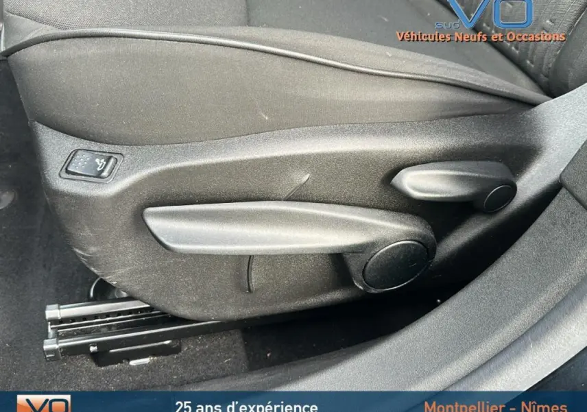 Détail des commandes de réglage manuel du siège avant côté gauche du FIAT 500X noir MY23 hybride.