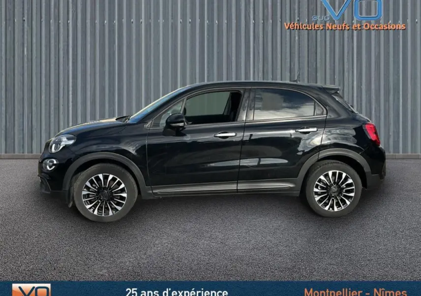 Profil côté gauche d'un FIAT 500X noir MY23 avec jantes classiques 16 pouces sur fond industriel.