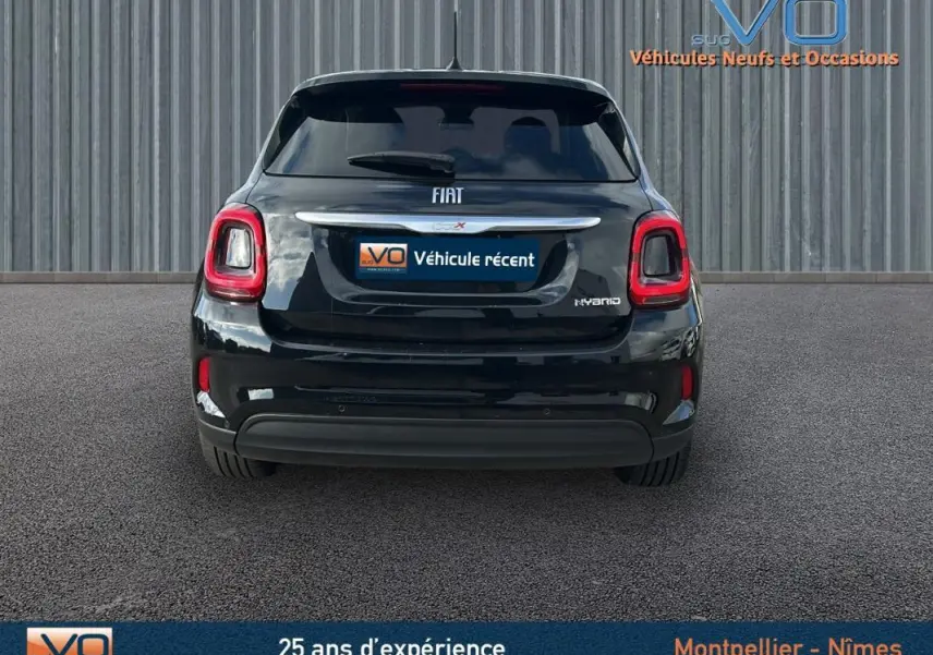 Vue arrière d'une FIAT 500X noire MY23 avec feux LED et logo Hybrid sur fond industriel gris.