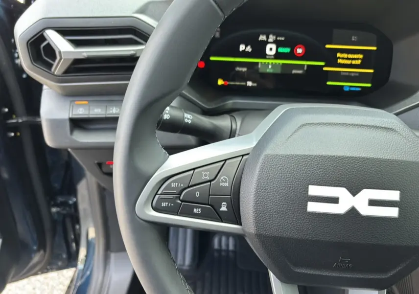 Gros plan sur le volant cuir et le tableau de bord digital du Dacia Bigster Hybrid 155, intérieur noir avec commandes au volant.