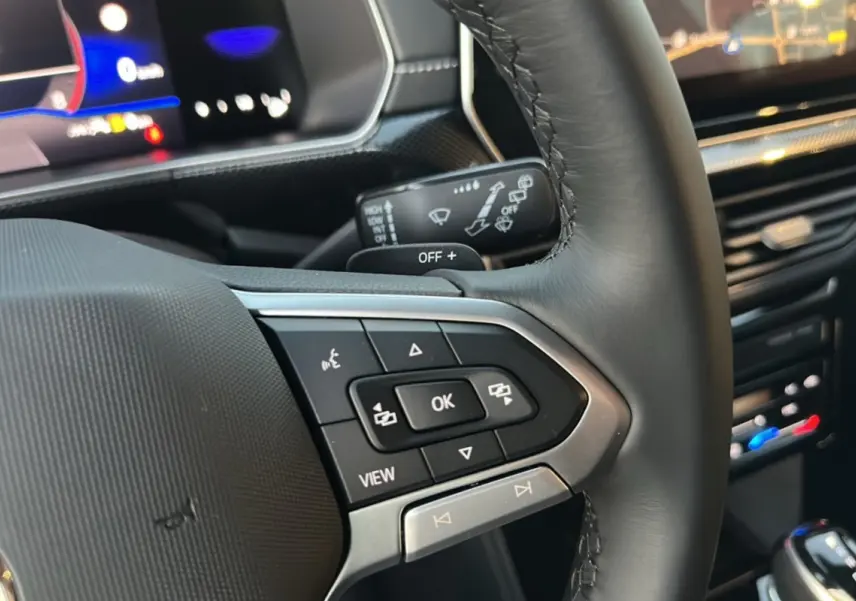 Gros plan sur les commandes multifonctions du volant cuir noir du Volkswagen T-Cross gris cendré 2025 TSI 116 DSG7 R-Line.