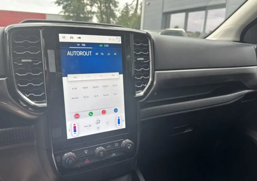 Vue rapprochée de la console centrale noire du Ford Ranger 2025 avec écran tactile vertical et commandes climatisation.