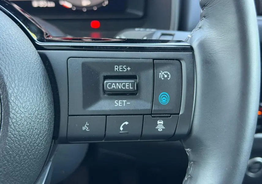 Gros plan sur les commandes de régulateur de vitesse au volant cuir noir du Nissan Qashqai Tekna 2022.