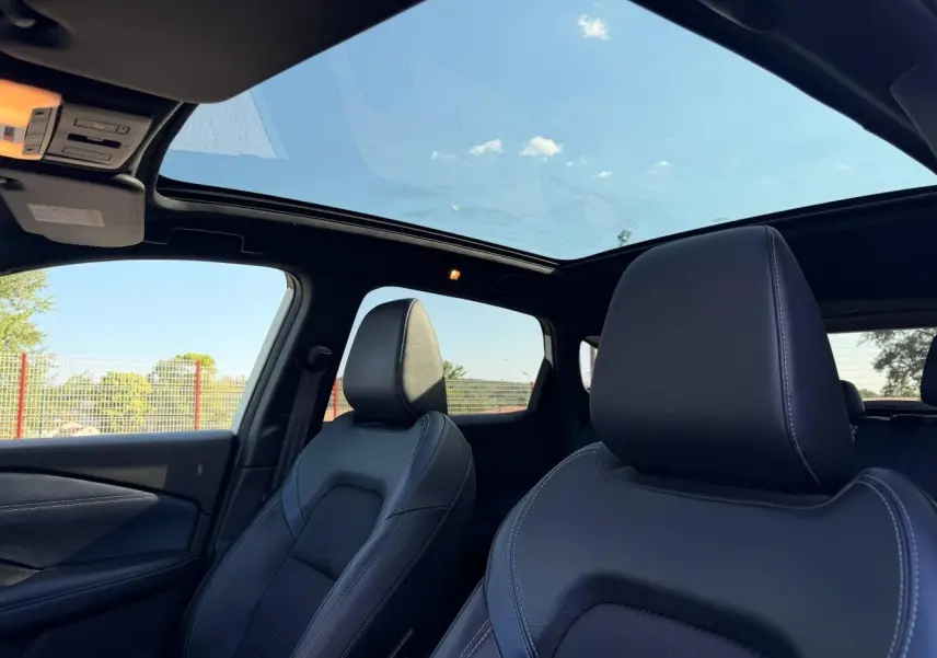 Vue intérieure avant du Nissan Qashqai 2022 avec sièges cuir noirs et toit panoramique ouvrant.
