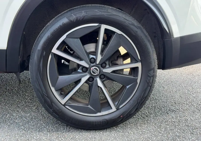 Gros plan sur la roue avant droite avec jante alliage noire et argent du Nissan Qashqai blanc.