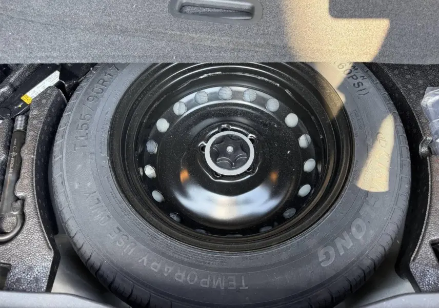 Roue de secours noire vue de dessus dans le coffre du Nissan Qashqai 1.3 Mild Hybrid rouge 2022.