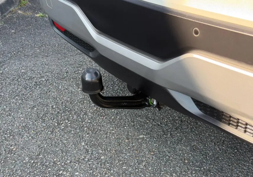 Gros plan sur l'attelage noir sous le pare-chocs arrière gris clair du Nissan Qashqai 2022.