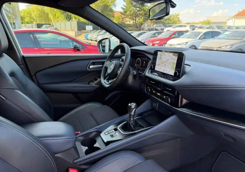 Vue intérieure côté conducteur du Nissan Qashqai 2022 Tekna, volant cuir, écran tactile et levier de vitesses manuel.