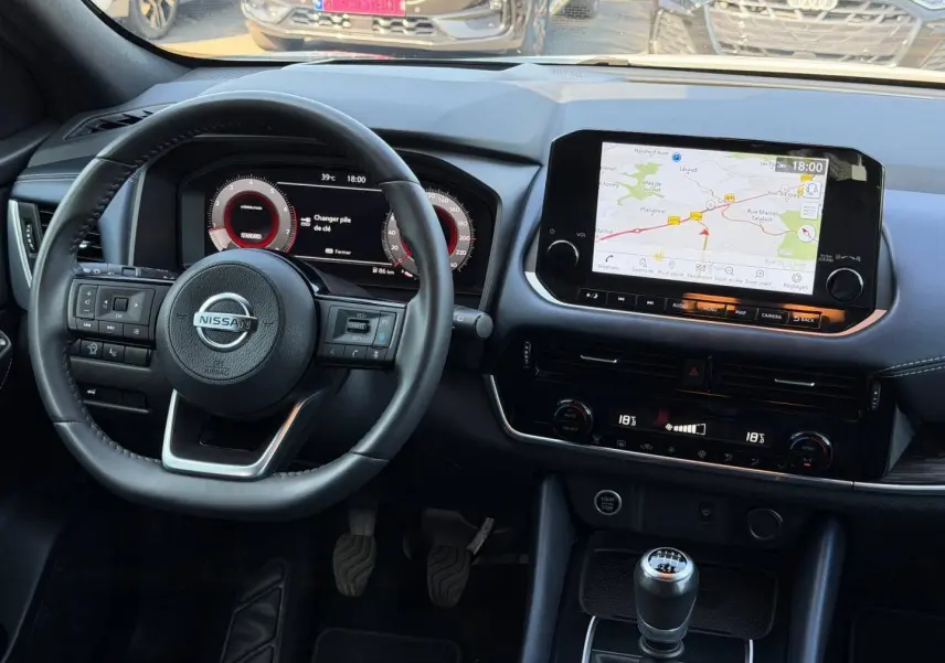 Vue intérieure frontale du tableau de bord du Nissan Qashqai 2022 avec volant cuir, écran tactile GPS et boîte manuelle.