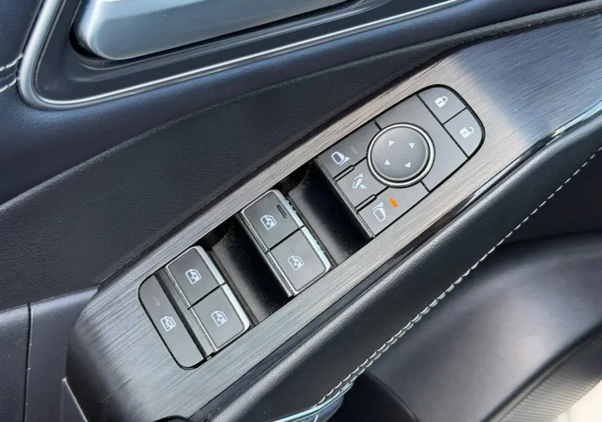 Gros plan sur la commande des vitres et rétroviseurs côté conducteur intérieur noir du Nissan Qashqai Tekna 2022.