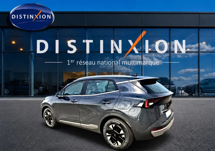 KIA SPORTAGE 1.6 hybride gris eclipse vu en 3/4 arrière droit devant un showroom Distinxion.