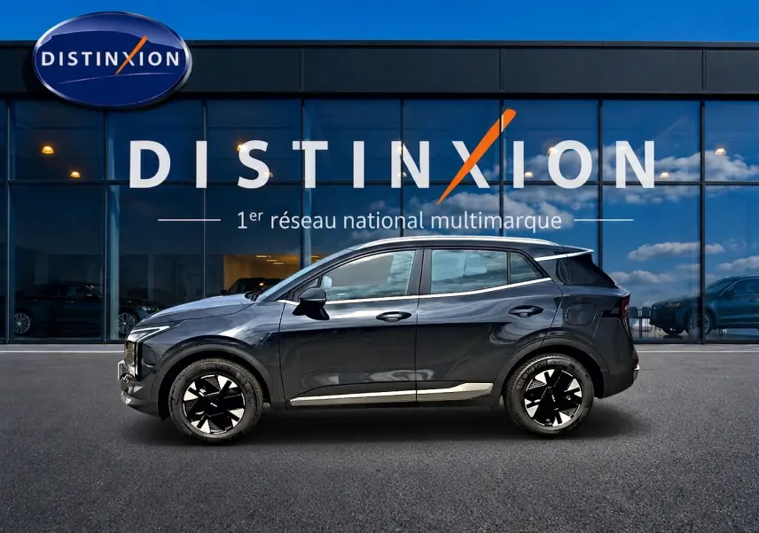 Vue latérale droite d'un KIA SPORTAGE 1.6 hybride gris eclipse avec jantes alu noires et barres de toit visibles.