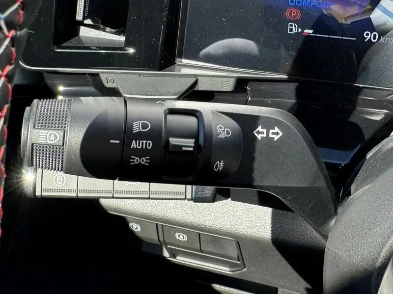 Gros plan sur la commande des feux et clignotants du Renault Austral blanc nacré, avec tableau de bord numérique en arrière-plan.