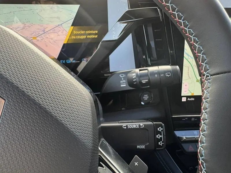 Gros plan sur la partie gauche du volant noir avec surpiqûres tricolores et commandes multifonctions du Renault Austral blanc nacré 2025.
