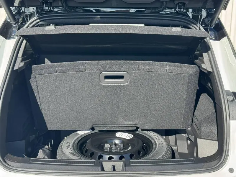 Coffre ouvert du Renault Austral blanc nacré brillant, montrant la roue de secours sous la tablette cache-bagages.