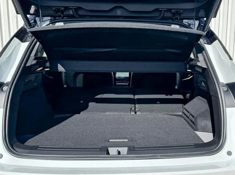 Coffre ouvert en vue arrière du Renault Austral blanc nacré brillant avec banquette arrière rabattue et tablette cache-bagages relevée