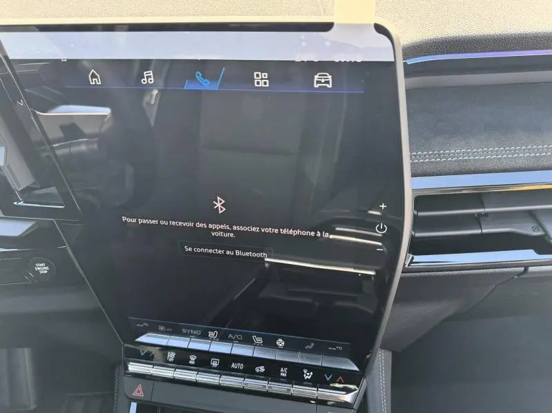Écran tactile central du tableau de bord du Renault Austral blanc nacré, avec commandes clim et Bluetooth affichés.