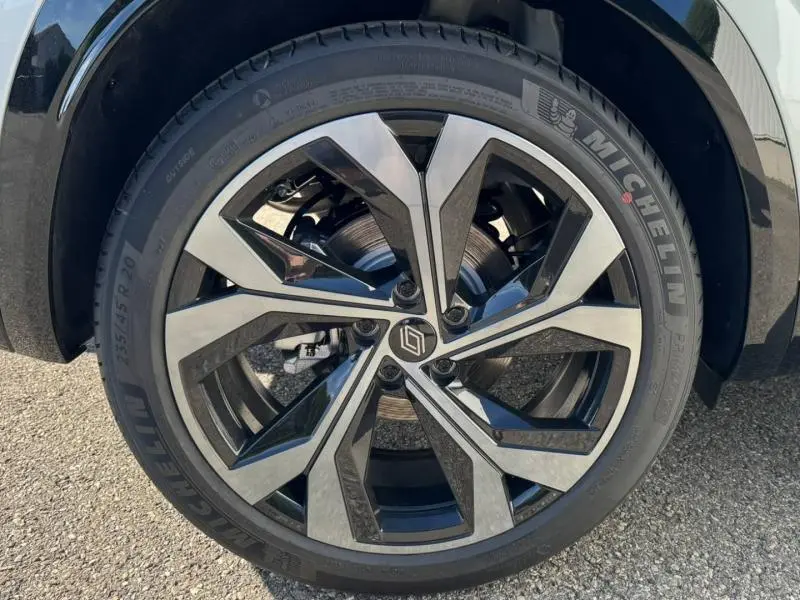 Gros plan sur la jante alu noire et argentée du Renault Austral blanc nacré brillant, soulignant son design moderne.