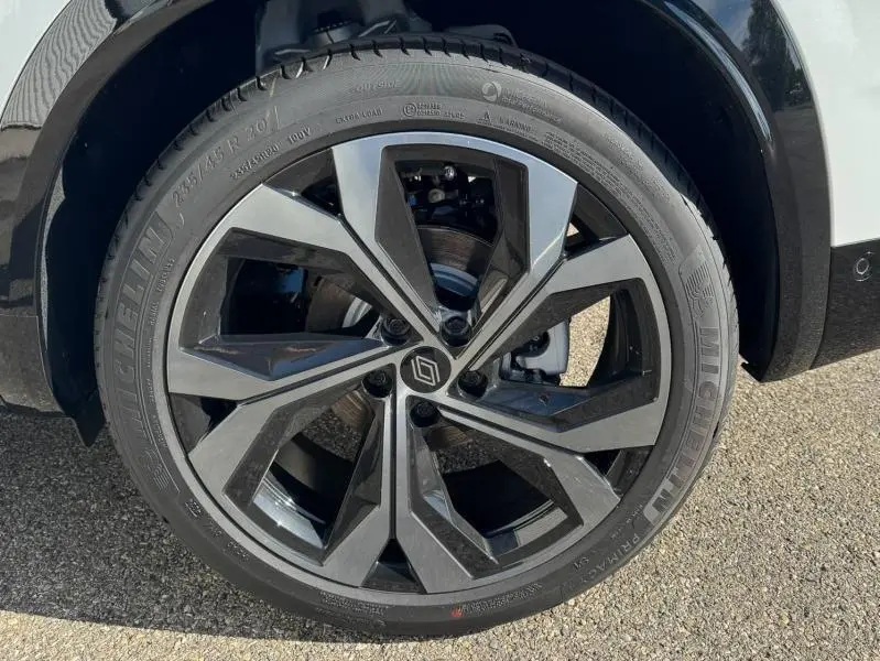 Gros plan sur la jante alu noire et grise du côté gauche d'un Renault Austral blanc nacré brillant 2025.