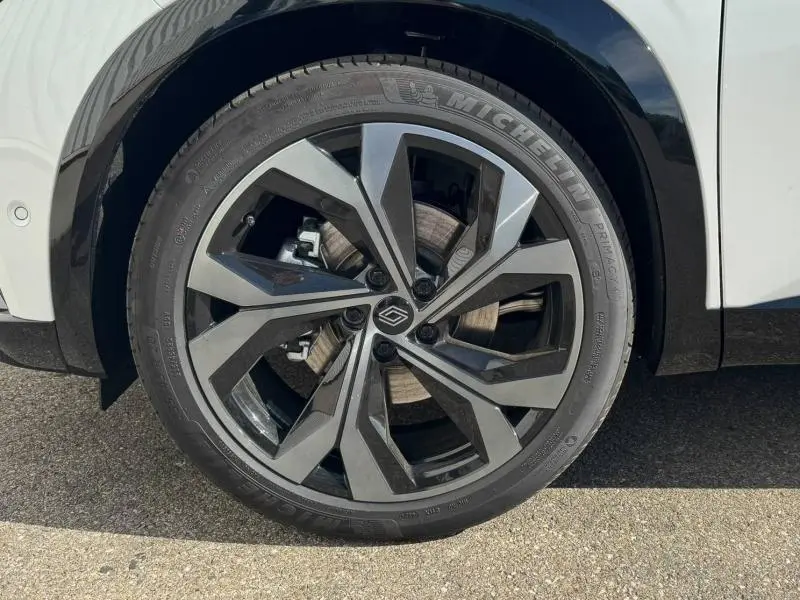 Gros plan sur la jante alu au design géométrique du côté gauche d'un Renault Austral blanc nacré brillant 2025.