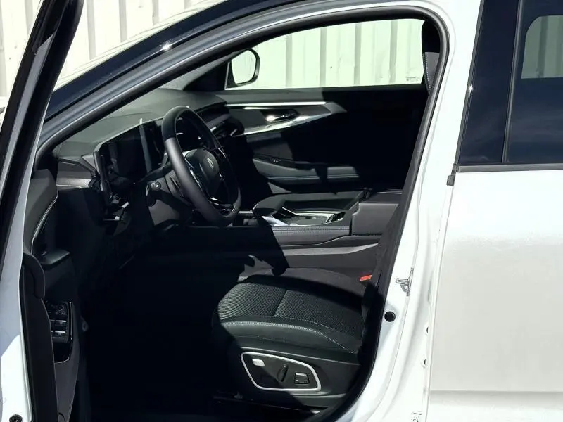 Intérieur côté conducteur du Renault Austral blanc nacré, mettant en valeur le siège et le tableau de bord moderne.