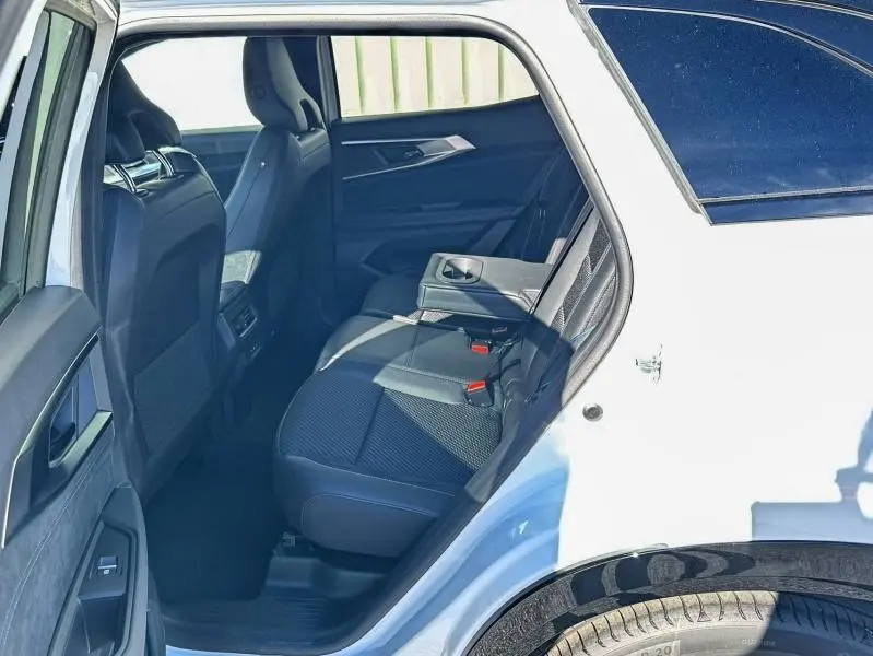 Vue côté gauche arrière du Renault Austral blanc nacré brillant, montrant les sièges arrière en tissu carbone et alcantara avec accoudoir central abaissé.