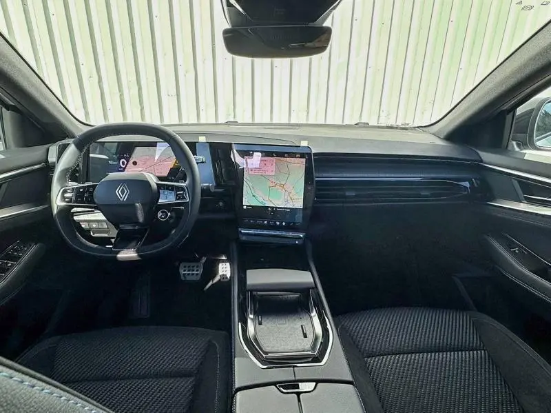 Vue intérieure frontale du tableau de bord du Renault Austral blanc nacré avec écran tactile vertical et volant multifonction.