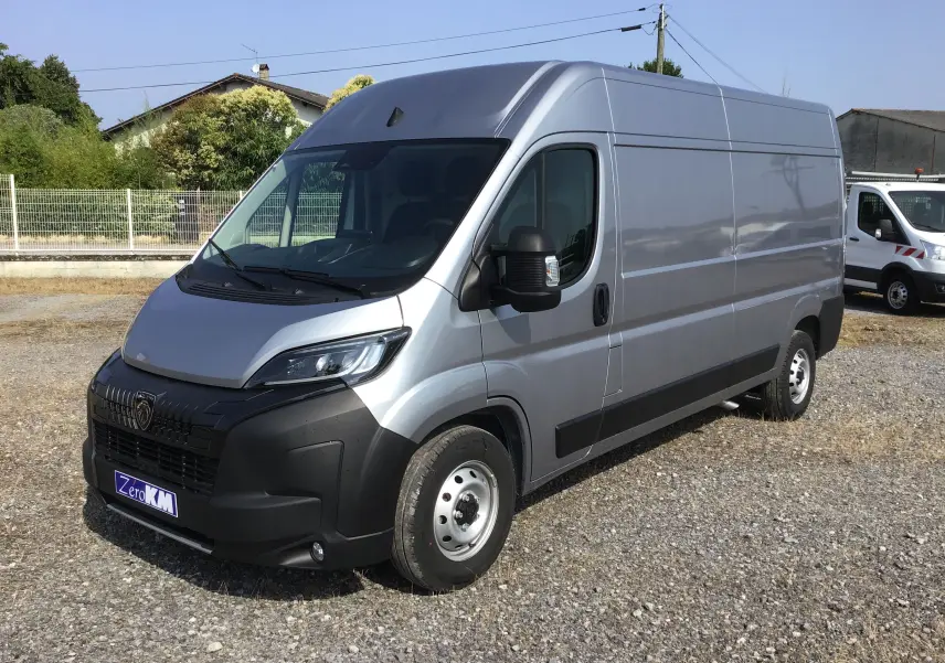 Fourgon Peugeot Boxer gris Artense vu en 3/4 avant droit, avec calandre noire et projecteurs LED visibles.