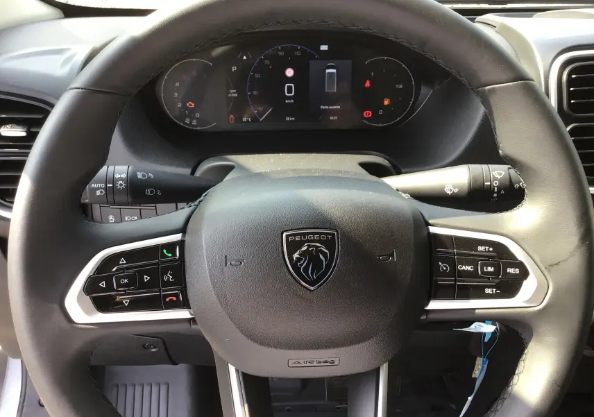 Vue rapprochée du volant noir de PEUGEOT Boxer Fourgon gris Artense, avec commandes intégrées et tableau de bord digital.