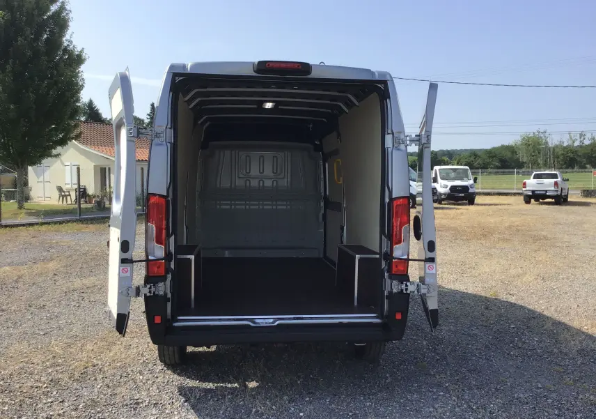 Vue arrière du Peugeot Boxer Fourgon gris Artense 2025 avec portes ouvertes dévoilant l'espace de chargement vide.