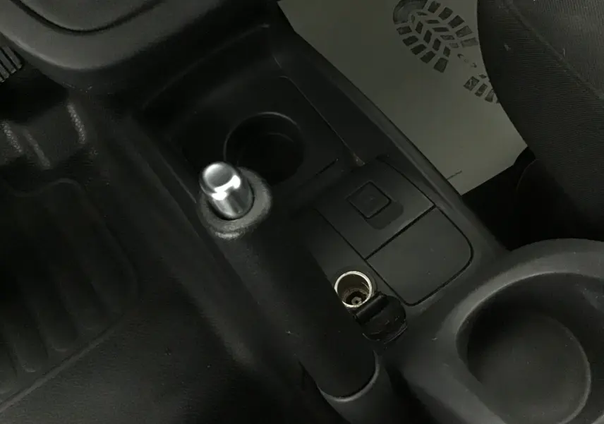 Vue rapprochée de la console centrale du Renault Kangoo blanc 2021, montrant le frein à main et prise 12V.