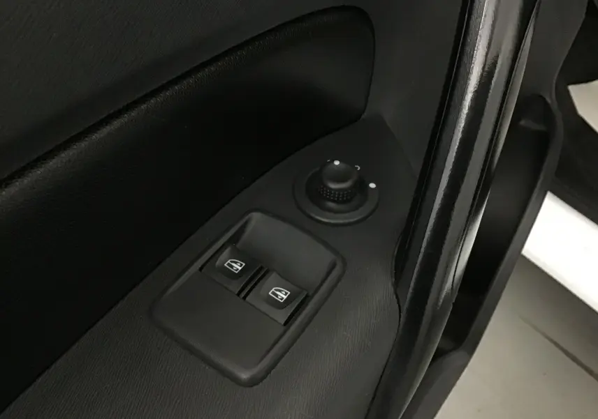 Gros plan sur les commandes électriques des vitres et le réglage des rétroviseurs sur la porte côté gauche d’un Renault Kangoo blanc 2021.