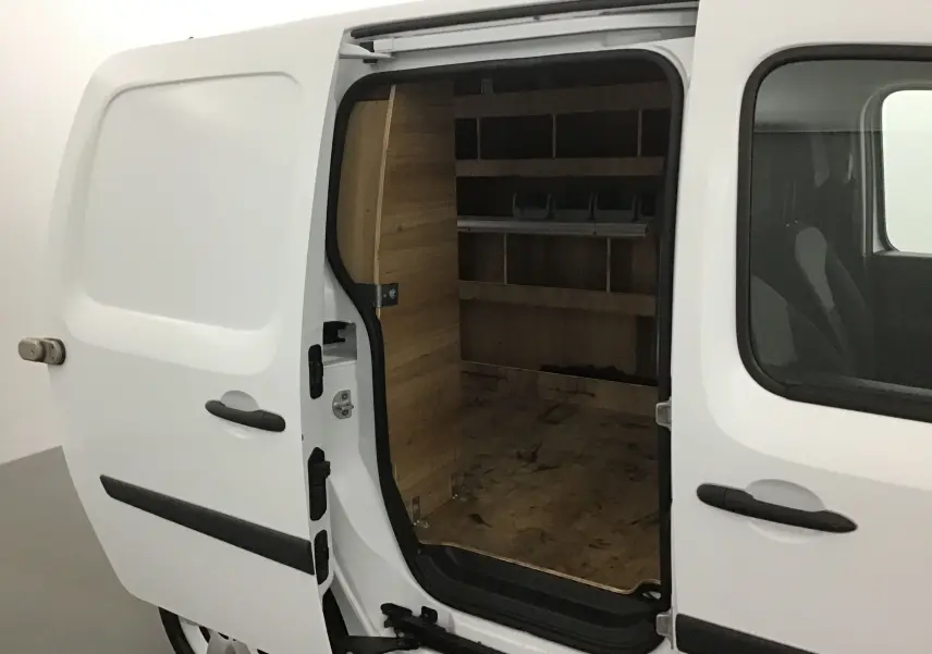 Vue latérale gauche d'un Renault Kangoo blanc 2021 avec porte coulissante ouverte révélant un aménagement intérieur en bois.