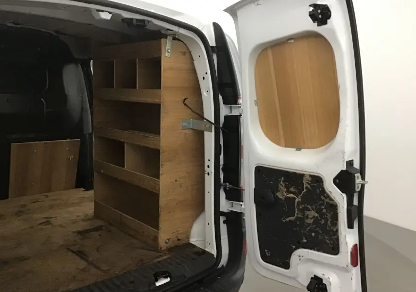 Vue arrière droite d'un Renault Kangoo blanc 2021 avec portes ouvertes montrant l'aménagement bois intérieur utilitaire.
