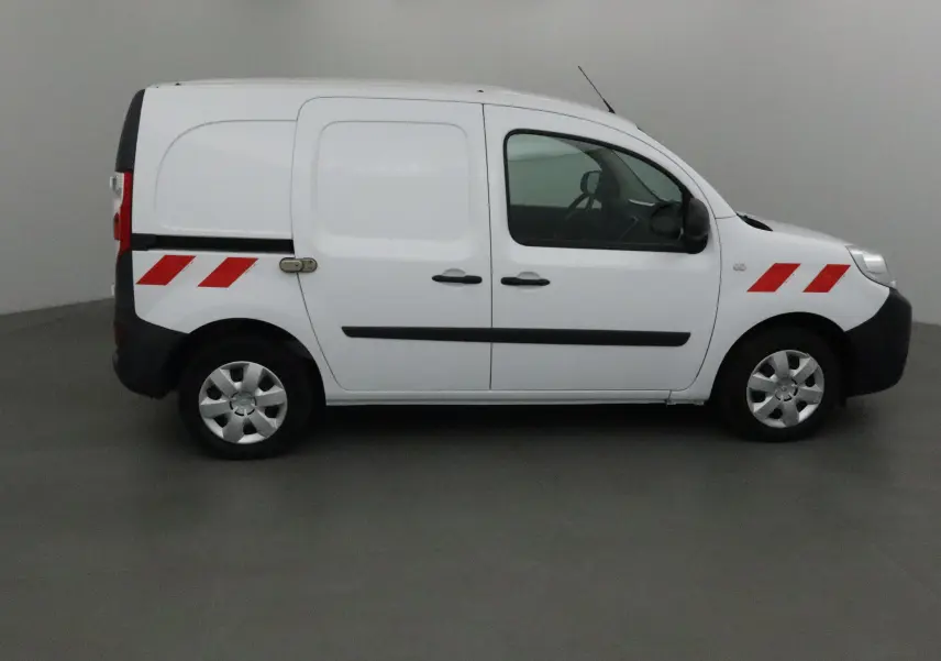 Profil côté droit d'un utilitaire Renault Kangoo blanc avec bandes rouges réfléchissantes sur les ailes avant et arrière.