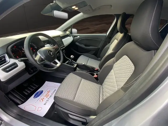 Intérieur avant droit de la Renault Clio V TCE 90 Evolution gris Highland, sellerie tissu noir et beige, volant multifonction.