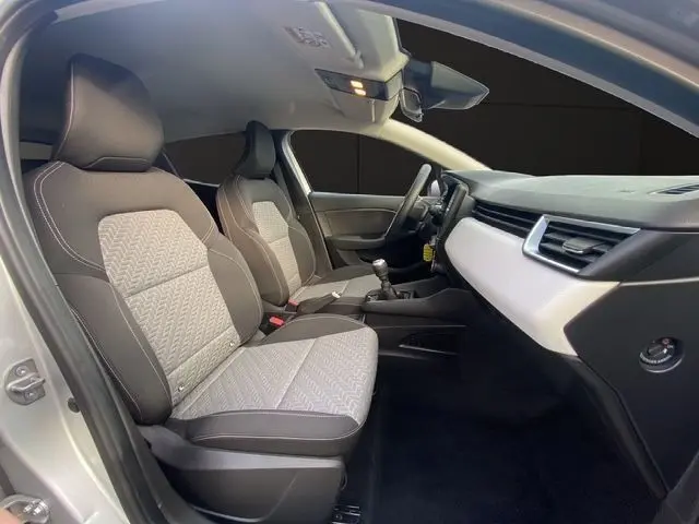 Vue intérieure côté conducteur de la Renault Clio V TCE 90 Evolution, sellerie tissu noir et beige, tableau de bord clair.