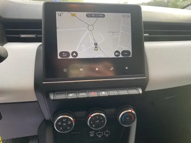 Vue rapprochée de la console centrale de la Renault Clio V gris Highland, avec écran tactile 7'' et commandes climatisation manuelle.