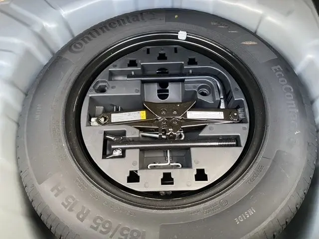 Gros plan sur la roue de secours et le cric dans le compartiment de coffre d'une Renault Clio V gris Highland.