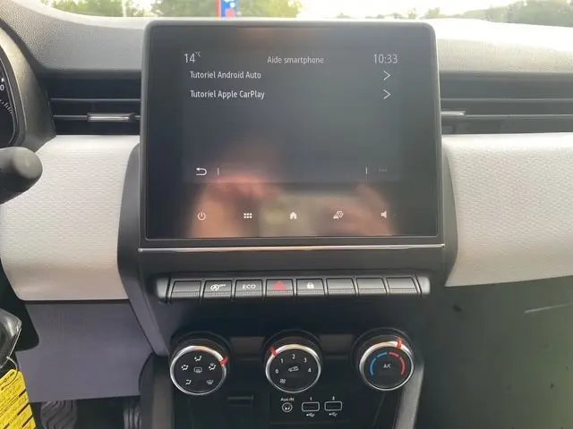 Vue rapprochée du tableau de bord de la Renault Clio V avec écran tactile 7 pouces et commandes de climatisation manuelle.