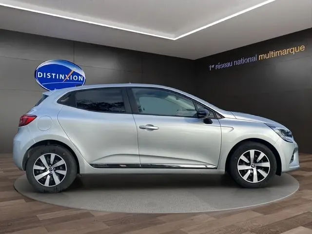 Profil droit de la Renault Clio V gris Highland avec vitres arrière surteintées et jantes alliage en intérieur showroom.